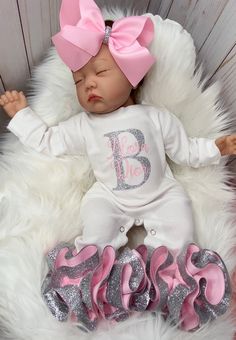 a baby doll with pink and silver hair laying on top of a white fur rug