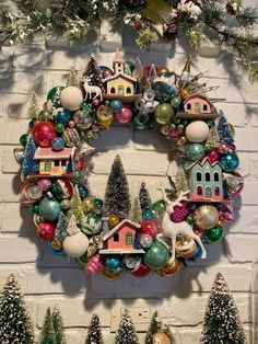 a christmas wreath is hanging on the wall next to other ornaments and trees in front of a white brick wall