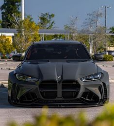 the front end of a gray sports car parked in a parking lot with other cars behind it