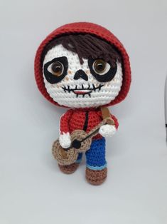 a crocheted doll is posed next to a cell phone