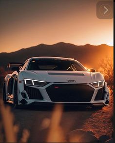 a white sports car parked on the side of a road at sunset with mountains in the background