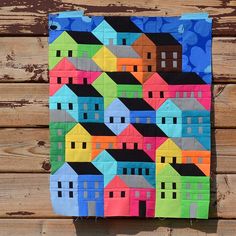 a colorful quilt is hanging on a wooden wall