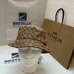 Coach Signature Khaki And Black Reversible Bucket Hat, One Size Fit All Coach Hat, Luxury Brown Brimmed Hat, Designer Adjustable Bucket Hat With Curved Brim, Designer Beige Adjustable Hat, Designer Adjustable Beige Hat, Classic Brown Bucket Hat With Short Brim, Luxury Brown Travel Hat, Designer Brown Hat For Travel, Designer Adjustable Hats For Travel