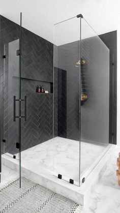 a walk in shower sitting next to a black and white tiled wall with shelves on each side