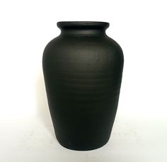 a black vase sitting on top of a white table