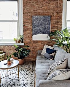 a living room filled with lots of furniture and plants on top of a brick wall