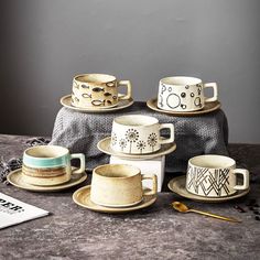 a table topped with cups and saucers on top of a cloth covered tablecloth