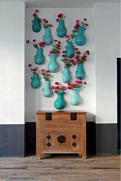 there are many vases on the wall with flowers in them