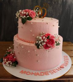 a three tiered pink cake with flowers on top