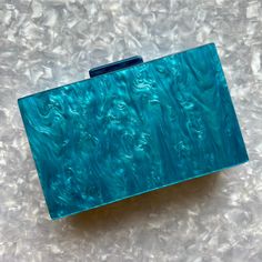 This party box acrylic clutch features a mesmerizing blue hand-swirled acrylic exterior. Push open the matching acrylic top clasp and inside you will find a black lined interior.  Comes with optional gold-toned crossbody chain to carry as a shoulder bag or you can add one of our acrylic chain bag straps for even more style. Fits an iPhone Plus with case.  Details:  ▪️Length: 7", Height: 4. 25", Depth: 2" ▪️Materials: acrylic, plated metals, cotton/polyester lining.   Small variations can ha Modern Blue Clutch For Formal Occasions, Trendy Blue Clutch For Formal Occasions, Trendy Blue Evening Clutch, Blue Rectangular Clutch For Events, Blue Rectangular Clutch For Formal Occasions, Trendy Blue Clutch For Gift, Blue Rectangular Clutch For Evening, Acrylic Clutch, Box Purse