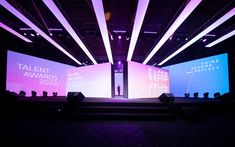 the stage is lit up with purple and blue lights for an award ceremony or conference