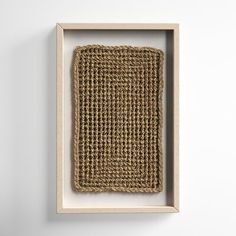 an empty wooden frame with a woven piece in it's center on a white wall