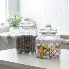 two glass jars filled with candy sitting on top of a counter