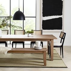 a dining room table with chairs and a bench in front of a large painting on the wall