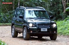 a black suv driving down a dirt road