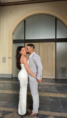 a man and woman standing next to each other in front of a building with an arched doorway