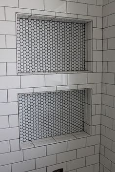 a white tiled bathroom with two shelves on the wall