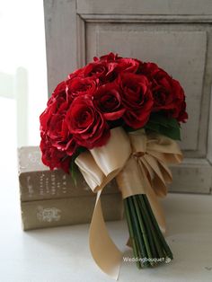 a bouquet of red roses sitting on top of a table next to a stack of books