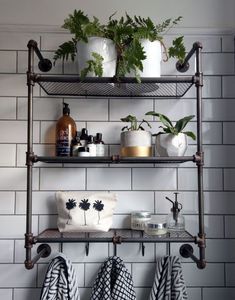 two shelves with towels, plants and other items on them in front of a white tiled wall