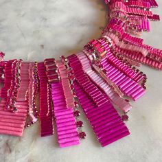 a pink necklace with lots of different colored beads and chains hanging from it's sides