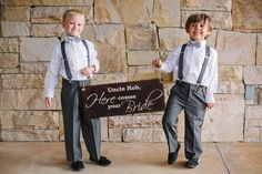 two young boys dressed in formal wear holding a sign