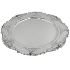 a silver plate with ornate designs on the rim and sides, set against a white background