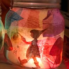 two mason jars with paper cut outs on them, one is holding a lit candle