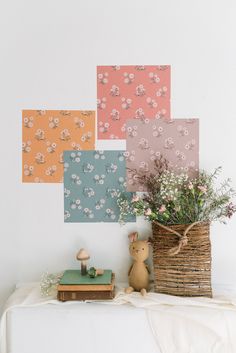 an arrangement of flowers in a basket next to a wall with four squares on it