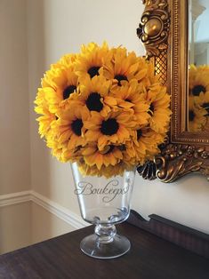 a vase filled with sunflowers sitting on top of a table next to a mirror