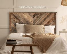 a bed with pillows and blankets on it in a room that has white walls, wooden headboard