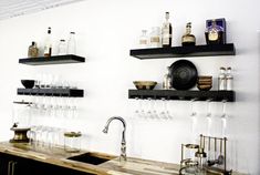 the kitchen counter is lined with wine glasses and liquor bottles, along with shelves on the wall