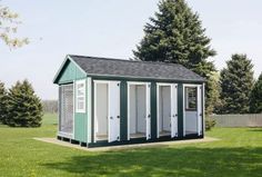 a small green and white shed sitting in the grass