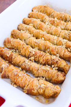 croissants are lined up in a white dish on a red and white tablecloth