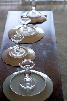 four wine glasses are lined up on a long table with white plates and silverware