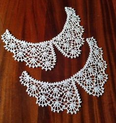 two white crocheted necklaces sitting on top of a wooden table