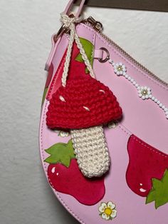 a pink purse with a crocheted strawberry on the front and a red mushroom on the back