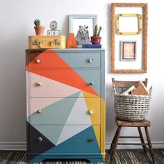 a colorful chest of drawers next to a chair