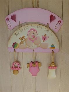 a wooden sign hanging from the side of a wall with baby's clothes on it