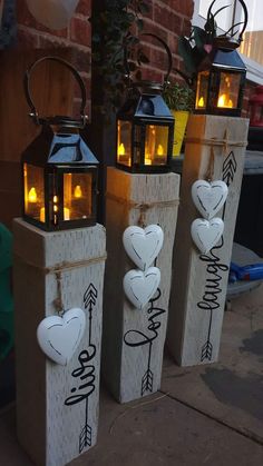 three lanterns with hearts and arrows are sitting on the sidewalk next to a brick wall