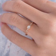 a woman's hand wearing a gold ring with three stones on the band and a diamond