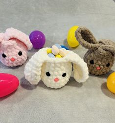 crocheted easter bunnies with bunny ears and an egg on the ground next to them