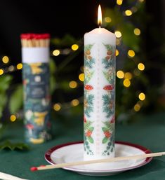 a lit candle sitting on top of a white plate next to a christmas tree with lights in the background