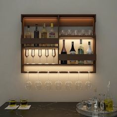 a bar with wine glasses and liquor bottles on the shelves above it is lit by lights