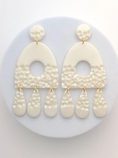 the earrings are white and have gold accents on them, with pearls hanging from each ear