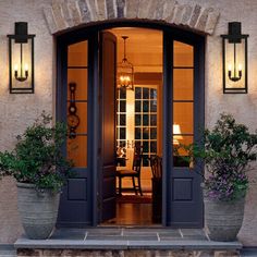 an entry way with potted plants and two lights on the side of the building