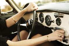 a woman sitting in the driver's seat of a car with her hands on the steering wheel