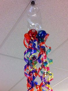 a bunch of colorful ribbons hanging from a ceiling in a room with a light fixture