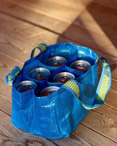 a blue bag filled with soda cans sitting on top of a wooden floor