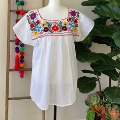 "The Yucatan embroidered top is beautifully made in Merida Yucatan, Mexico, each piece is fully hand embroidery. Details: - Size L/XL - measurements: Bust: 45\" - 29\" length(shoulder to bottom Hem) - Cotton thread Embroidered - Material: 100% Cotton - split sides - All items are shipped from the US All Mi Mundo Mexicano items are 100% handmade by artisans in Mexico. Each stitch and item is completely unique and one-of-a-kind, so you'll never find two that are exactly the same! All items may var Merida Yucatan Mexico, Embroidered Material, Traditional Flower, Mexican Blouse, Bright Boho, Ribbon Skirts, Yucatan Mexico, Embroidered Tunic Top, Flower Blouse