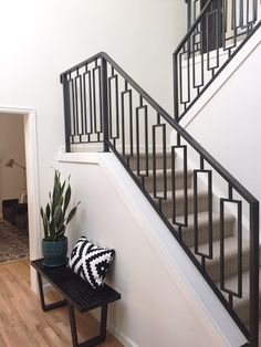 a black and white pillow sitting on top of a bench next to a stair case